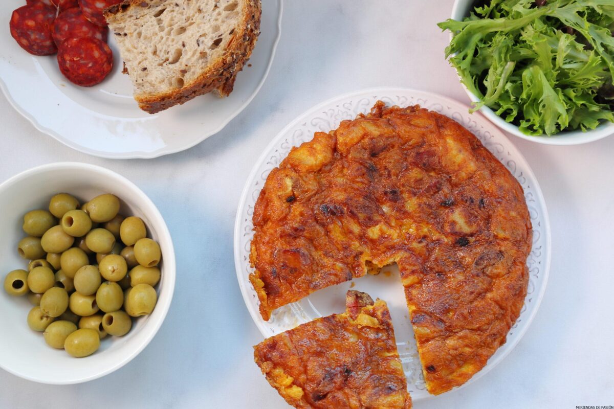 Green olives and Spanish Tortilla with chorizo in a table with greens and bread