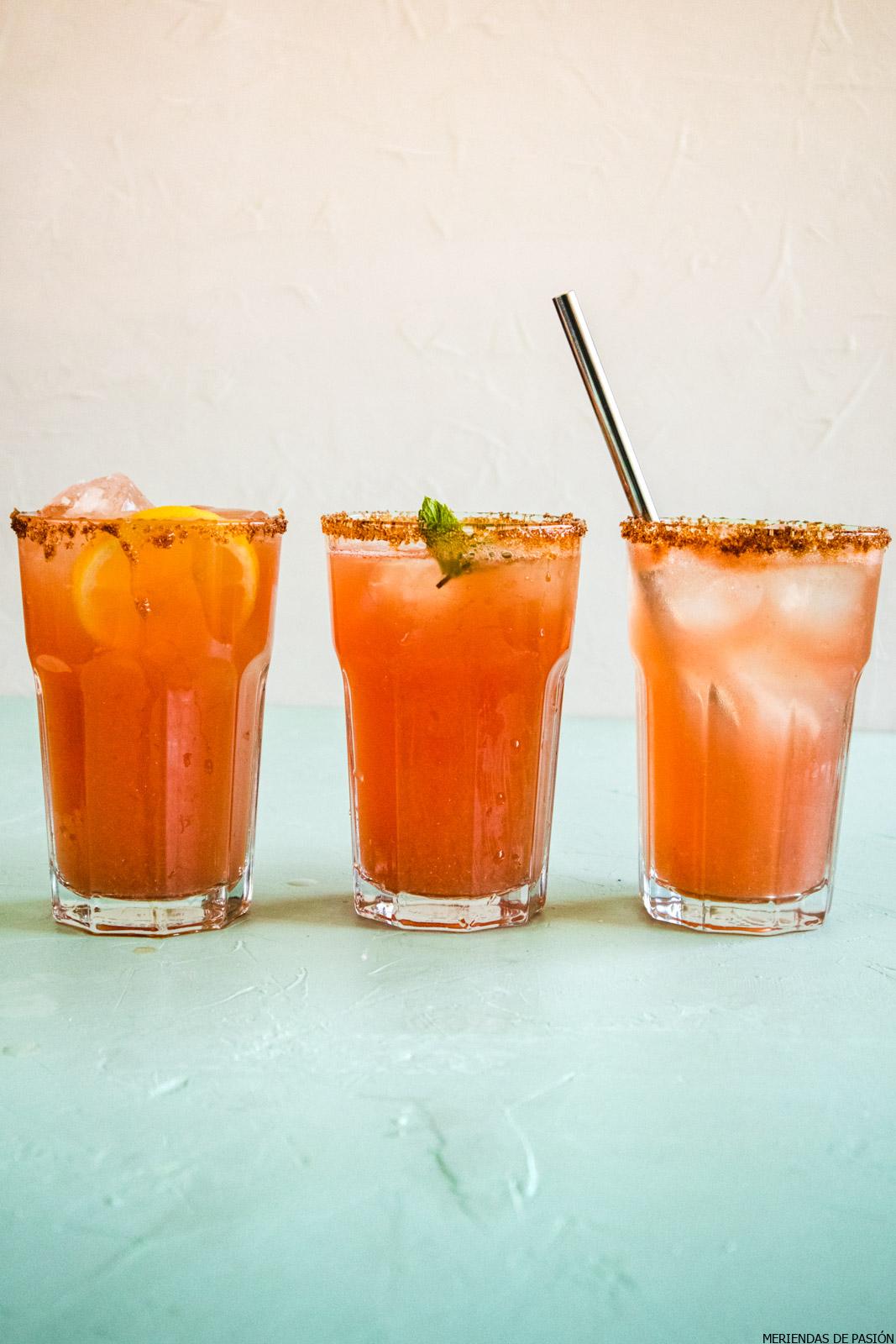 Three glasses of watermelon lemonade, with ice, lemon slices and some mint leaves.