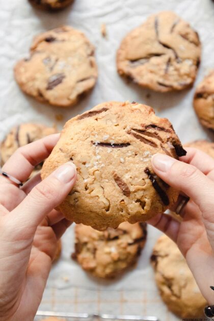 Una persona sosteniendo una galleta con chispas de chocolate.