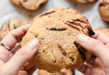 Una persona sosteniendo una galleta con chispas de chocolate.