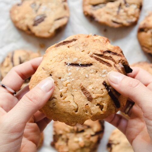 Una persona sosteniendo una galleta con chispas de chocolate.