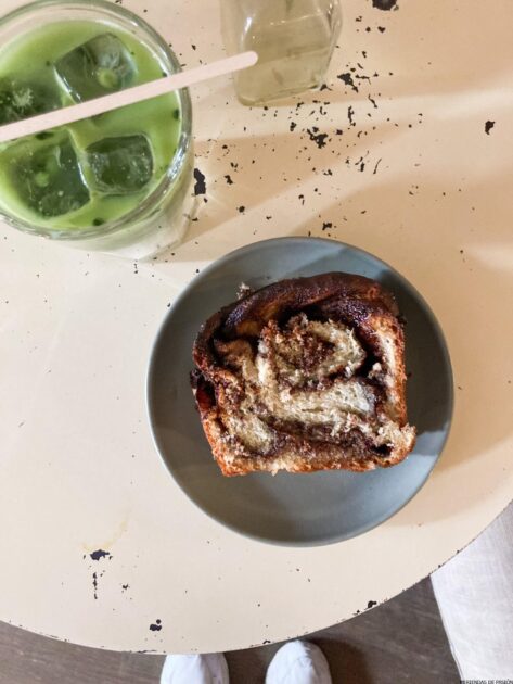 Un plato con un trozo de pan y una bebida encima.