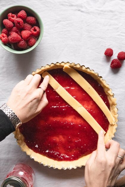 Una persona cortando una tarta de frambuesa con un cuchillo.