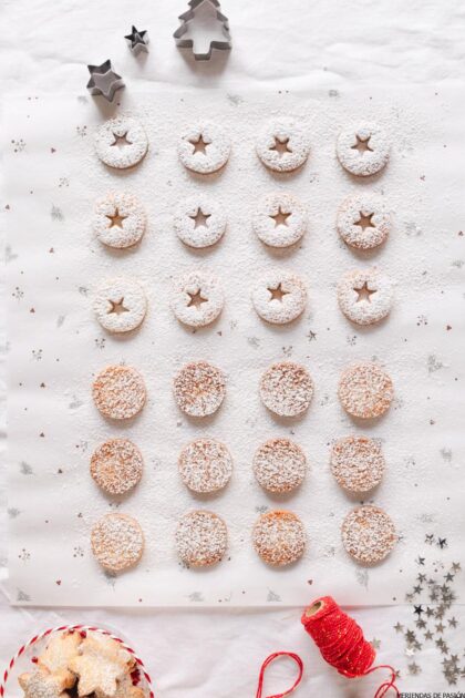 Galletas navideñas con azúcar en polvo en una bandeja para hornear.