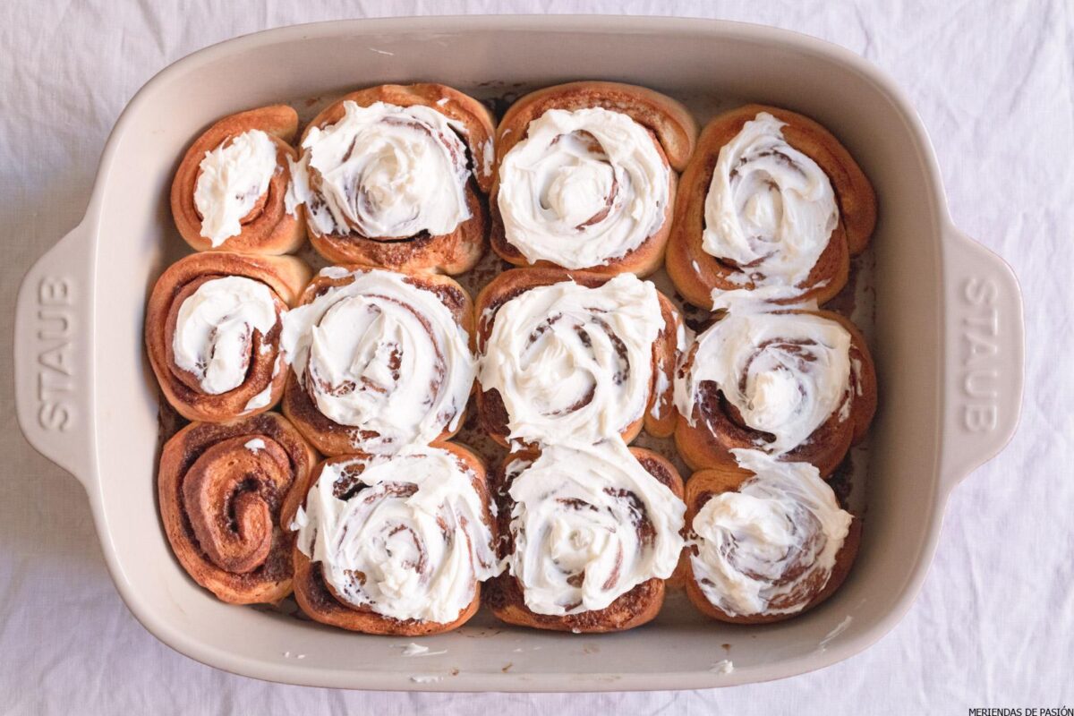 Rollitos de canela en una fuente para horno con crema batida.