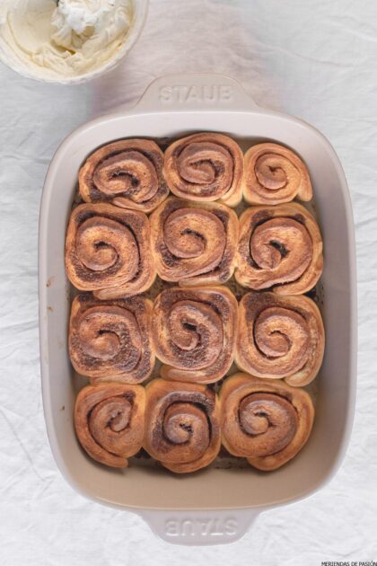 Rollitos de canela en una fuente para horno con una bola de helado.