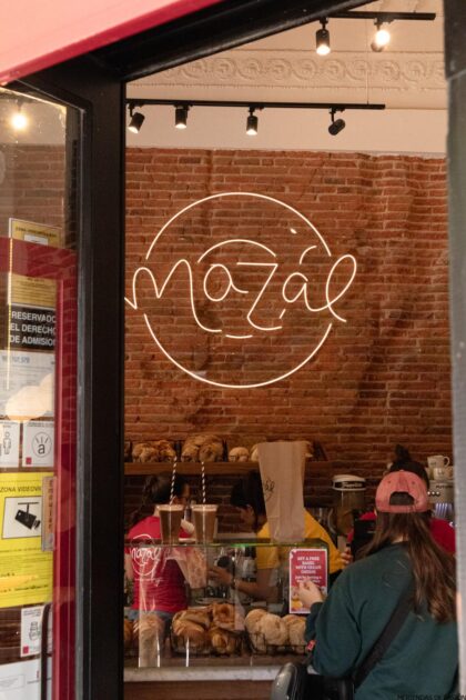 Una mujer está parada frente a una panadería con un cartel que dice mozaal.