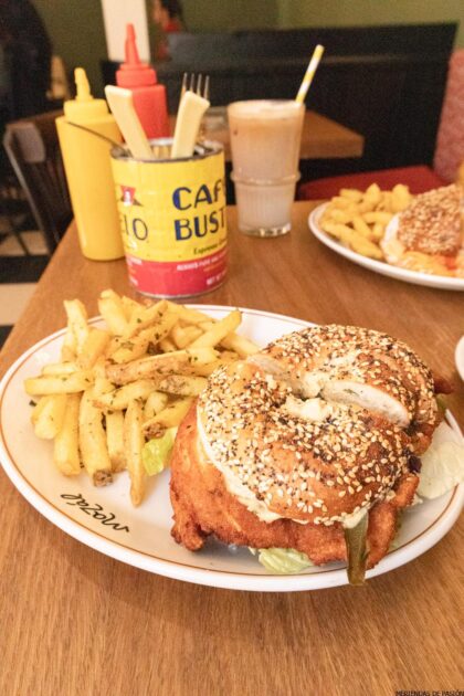 Un sándwich de bagel con patatas fritas y ketchup sobre una mesa.