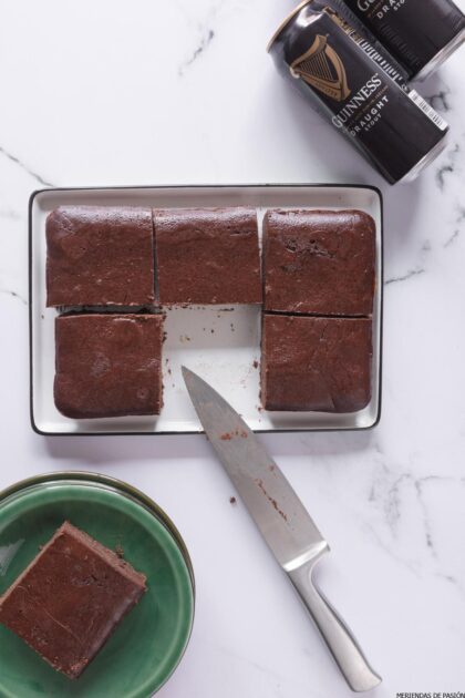 Brownies de chocolate Guinness en una bandeja con un cuchillo y latas.