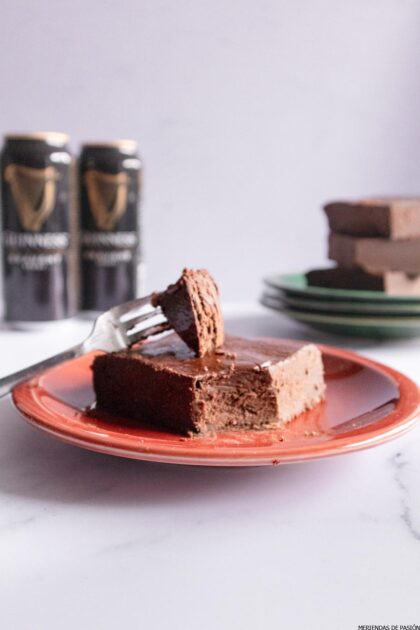 Un trozo de tarta de chocolate en un plato junto a una lata de Guinness.