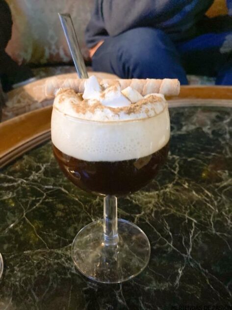 Un vaso de café con crema batida y malvaviscos sobre una mesa de mármol.