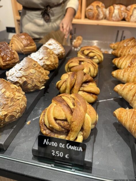 Productos de panadería variados expuestos en una panadería, con especial atención al "nudo de canela" a un precio de 2,50 euros.